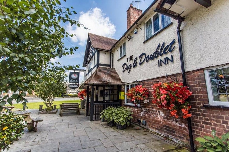 Exterior view of The Dog & Doublet Inn with flowers and sign