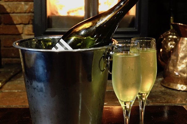 A bottle of champagne in an ice bucket with two flutes beside it.