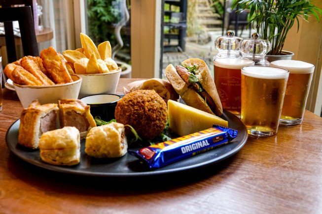 A variety of pub food including chips, pies, and drinks on a table