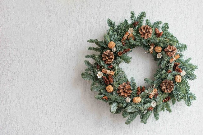 A festive wreath adorned with pinecones and nuts on a white wall.