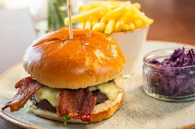 A bacon cheeseburger with fries and coleslaw on a plate